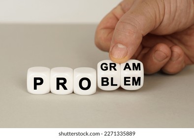 On a gray surface are white cubes with the inscription - PROGRAM or PROBLEM. Two dice in hand. Business concept.