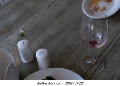 On A Gray Wooden Table Stands A White Dirty Plate And An Empty Glass Of Red Wine