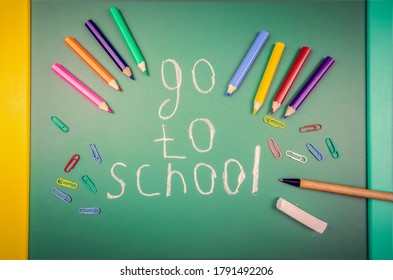 En un pizarrón verde se escribe para ir a la escuela, al lado hay lápices, lápices, clips de papel de colores y un bolígrafo. Concepto de la escuela, año académico. Hermoso, divertido fondo de la escuela.