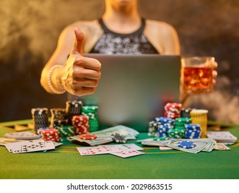 On The Green Cloth Of The Poker Table Laptop, Cards, Chips, Money. Young Woman Gambling In An Online Casino. Gambling Addiction, Online Casino, Poker. Focusing On The Foreground.