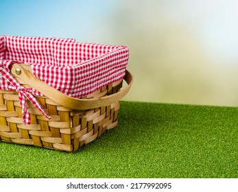 On The Green Grass A Picnic Basket On A Light Blue Background. Family Vacation, Romantic Walk. Minimalism. There Are No People In The Photo. There Is Free Space To Insert.