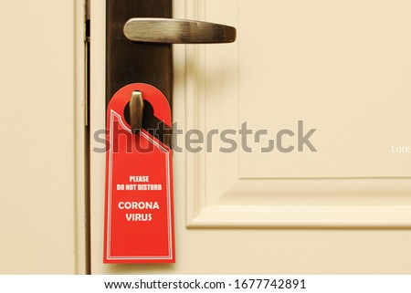 On the handle hangs a "do not disturb, coronavirus" sign. Quarantine at the hotel, dangerous travel. Business trip to other countries. Isolation, stay home.