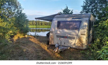 On the high bank of the river among the trees stands a caravan trailer with an awning. This creates comfort in resting and fishing