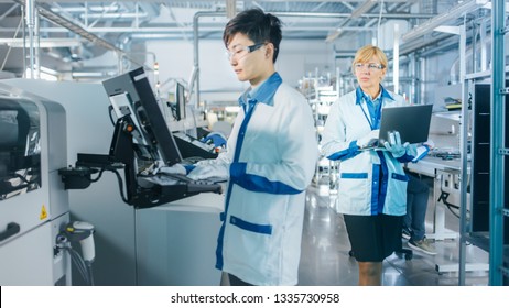 On High Tech Factory Asian Engineer Uses Computer for Programing Pick and Place Electronic Machinery for Printed Circuit Board Surface Mount Assembly Line. Production of PCB with SMT Machinery. - Shutterstock ID 1335730958