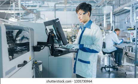 On High Tech Factory Asian Engineer Uses Computer for Programing Pick and Place Electronic Machinery for Printed Circuit Board Surface Mount Assembly Line. Production of PCB with SMT Machinery. - Shutterstock ID 1335730964