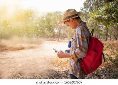 On Holidays, Asian Boys Aged 6 To 8 Years Wear A Red Backpack. Wearing A Long Sleeved Shirt. Are Doing Long-distance Activities For Outdoor Adventures In The Forest, Outdoor Adventure Concept