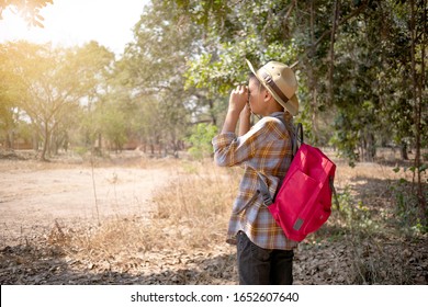 On Holidays, Asian Boys Aged 6 To 8 Years Wear A Red Backpack. Wearing A Long Sleeved Shirt. Are Doing Long-distance Activities For Outdoor Adventures In The Forest, Outdoor Adventure Concept