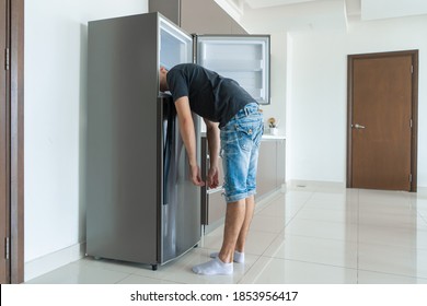 On a hot day, the guy cool down with his head in the refrigerator. Broken air conditioner.