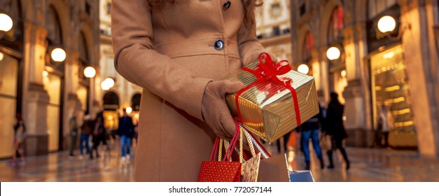 On a huge Christmas sales in Italian fashion capital. Closeup on Christmas gift and shopping bags in hands of woman with Christmas gift and shopping bags in Galleria Vittorio Emanuele II in Milan