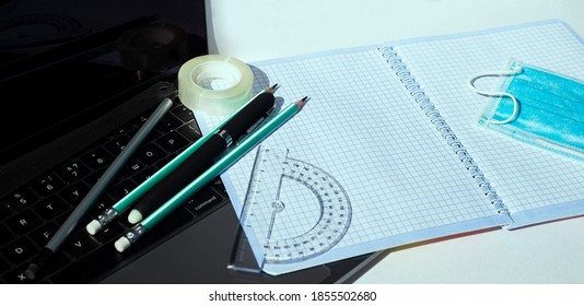  On The Laptop Keyboard Lie A Notebook Pencils Pens Ball-point Protractor Adhesive Tape And A Disposable Medical Mask.