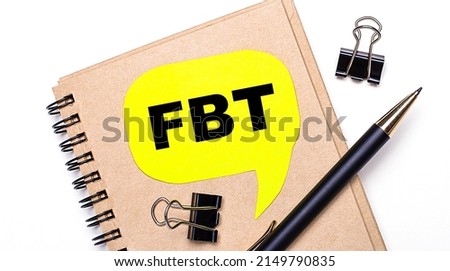 On a light background, a brown notebook, a black pen and paper clips, and a yellow card with the text FBT Fringe Benefit Tax. Business concept.