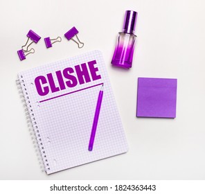 On A Light Background - A Lilac Gift, Perfume, Lilac Business Accessories And A Notebook With The Inscription CLICHE. Flat Lay. Female Business Concept