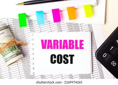 On A Light Background, A Pen, Dollars, A Notebook With The Text VARIABLE COST And Bright Stickers. Business Concept