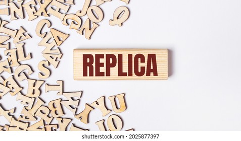 On a light background, wooden letters and a wooden block with the text REPLICA. Flat lay - Shutterstock ID 2025877397