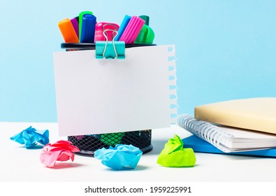 On light blue background there is stand and bright markers  notepads   multi  colored crumpled pieces paper  sheet paper and place to insert text  Template  Copy space