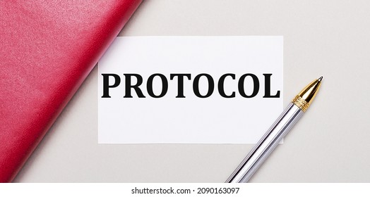 On a light gray background, there is a golden pen, a burgundy notebook and a white blank card with a place to insert text PROTOCOL Business concept.