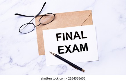 On A Light Marble Background, A Craft Envelope, Glasses, A Pen And A White Card With The Text FINAL EXAM