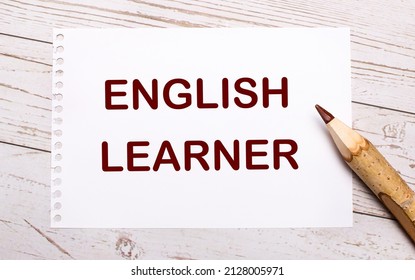 On A Light Wooden Background, A Colored Pencil And A White Sheet Of Paper With The Text ENGLISH LEARNER