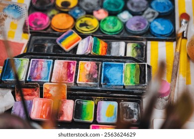 On a lovely table set for creativity, theres an array of vibrant watercolor paints alongside various brushes waiting to bring artistic visions to life. It invites inspiration for art enthusiasts