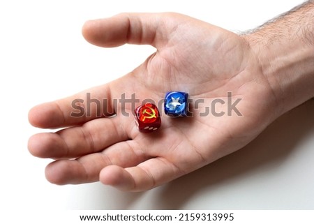 On the man's palm are two dice with images of the symbols of the hammer and sickle and white star. The concept is political game or ideology of communism and capitalism