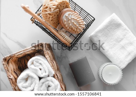 On a marble background a set of various bath accessories. Terry towel, soap, comb, oil, shampoo, loofah washcloth and candles. The view from the top