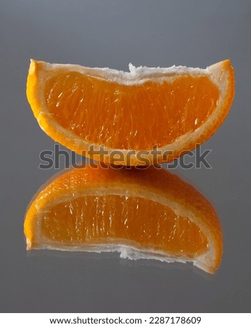 On the mirror table is a slice of oranges. from which the reflection comes.