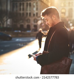 On My Way To The Office. Shot Of A Focused Young Man Texting On His Phone While Standing In The Busy Streets Of The City On His Way To Work.