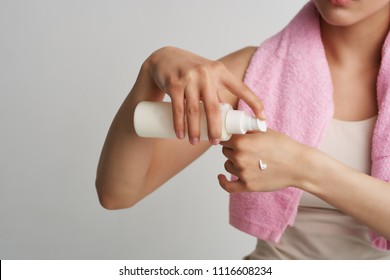   on the neck of a towel a woman squeezes the cream on her arm                             