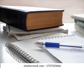 On the notebook lies a pen. Books and notebooks are nearby. Study, education, note taking, scientific work. Educational background with books, notebooks, pen.