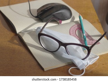 On The Notebook Is A Medical Mask, Glasses, Protractor, Pen. Concept - Protection From Coronavirus, Self-isolation Mode, Distance Learning