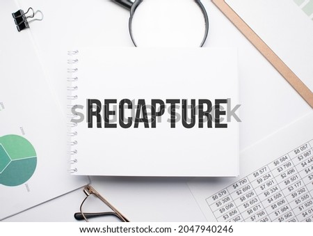 On the notepad for writing the text recapture, magnifier,charts and glasses.
