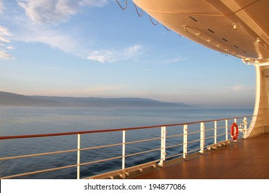 On the open deck of a cruise ship on a calm day, with the coast in the distance. - Powered by Shutterstock