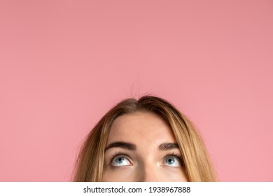 On a pink background, the half-face of a girl and her eyes looking up. Place for advertising, copy space. - Powered by Shutterstock