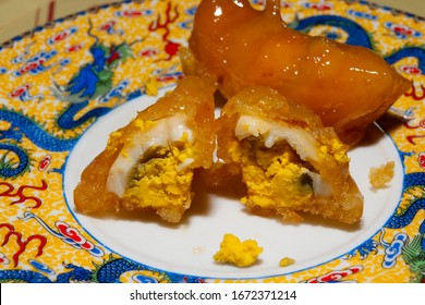 On The Plate Is A Cooked Broken Chicken Egg In Caramel. National Chinese Dish. The Photo Was Taken In Close-up. The Dessert Is Placed On A National Chinese Porcelain Plate With A Pattern.