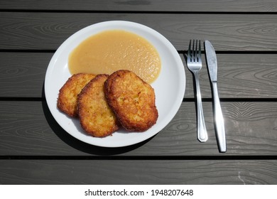 On A Plate Are Three Potato Pancakes With Applesauce And Cutlery Next To Them