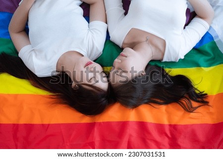 On a rainbow flag, an LGBT couples happily lie down, chatting, and teasing each other.