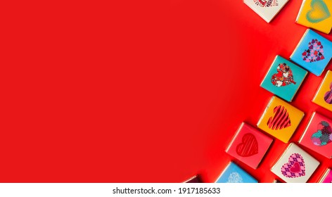 on a red background in the lower left corner there are small square chocolates in the cover with hearts, a banner - Shutterstock ID 1917185633