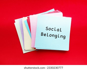 On red background, notepad with text written Social Belonging - feeling of inclusion or acceptance into group of people. sense of community connectness in social group