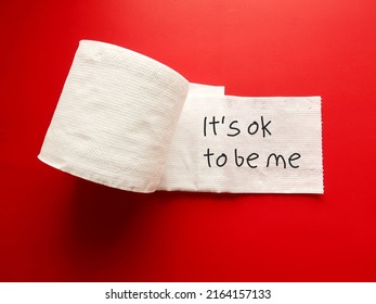 On Red Background, Toilet Paper With Handwriting 'It’s Ok To Be Me' Concept Of Using Positive Sentences Mantra Affirmation Will Immediately Change The Way We Think And Boost Self Esteem