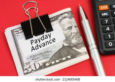On a red surface lies a calculator, a pen, dollars and paper with the inscription - Payday Advance