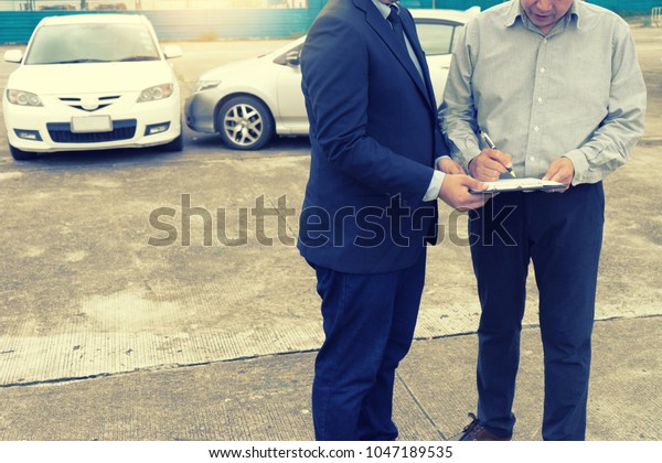 On the road car accident
insurance agent examining carcrash  owner and insurance staff make
paper form