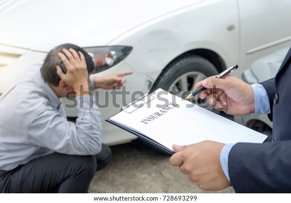 On the road car accident\
insurance agent examining crash  owner and insurance staff make\
paper form