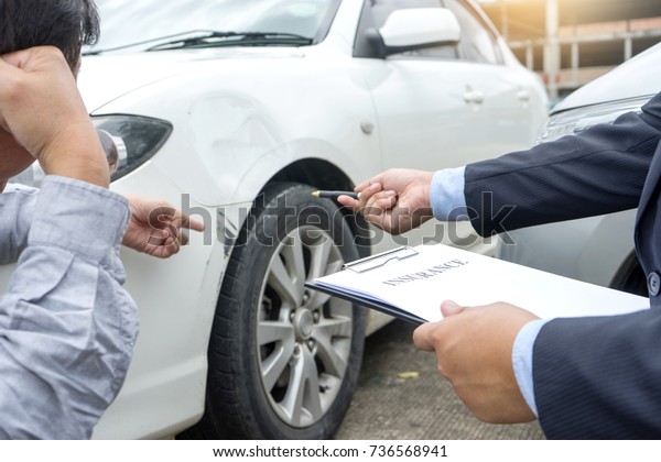 On the road car accident\
insurance agent examining carcrash  owner and insurance staff make\
paper form