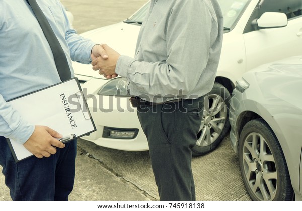 On the road car accident insurance\
agent examining car crash  owner and insurance staff make paper\
form, handshake for agreement about in insurance\
claim