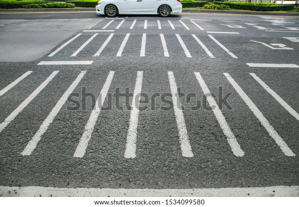 On the road with white lines is a warning\
sign for cars passing by to reduce speed. And the image with white\
lead lines in the\
background.