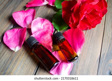 On the rose petals are two bottles of essential oil. Aromatic oil in dark bottles on rose petals. Tea rose - aromatic oil for massage,