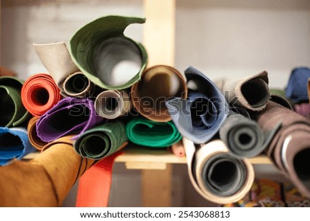 on the shelf of the leather workshop are rolls of multicolored leather for making bags purses and other leather accessories. High quality photo