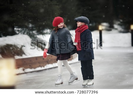 On the skating ring. Cute boy and girl are skating in the evening. Image with selective focus and toning.