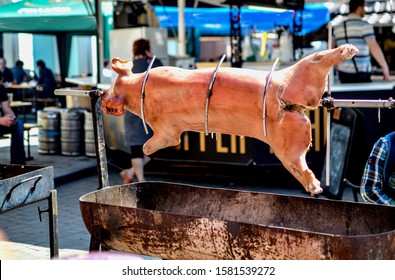 On A Spit Preparing A Huge Milk Juicy Appetizing Pig At A Street Food Festival