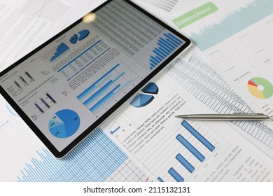 On statistical reports lies a tablet with charts on the screen